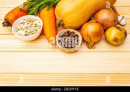Frische Zutat für Kürbissuppe. Kürbis, Zwiebel, Karotte, Kartoffel, Gewürze, Samen, Pfeffermischung, Salz, Dill. Gemüse auf Holzgrund Stockfoto