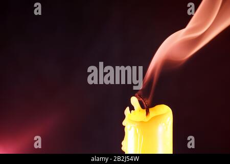 Kerze nach dem Ausblasen der mit bunten Blitzen fotografierten Flamme im Studio Stockfoto