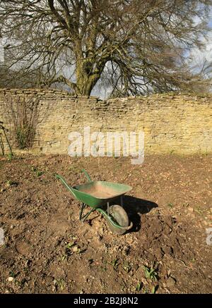 Eine Schubkarre, die bei der Vorbereitung von Blumenbeeten im Winter/Frühling verwendet wird. Stockfoto