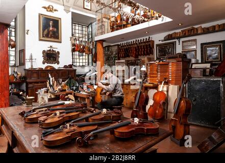 Lustiger Geigenbauer, der in einer Werkstatt an der Herstellung einer Geige arbeitet Stockfoto