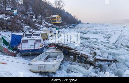 Zerstörte Boote an einem gefrorenen Donau-Fluss mit vielen Eiswürfeln in der Nähe von Belgrad, Zemun, Serbien Stockfoto