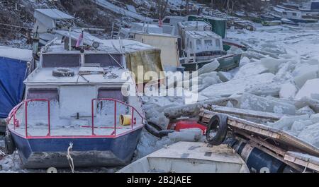 Viele zerstörte Boote an einem gefrorenen Donau-Fluss mit vielen Eiswürfeln in der Nähe von Belgrad, Zemun, Serbien Stockfoto