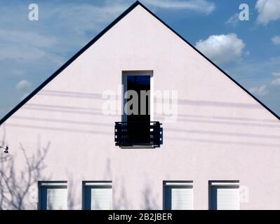 Modernes weißes Stuck mit Außendetails. Kleiner französischer Balkon und Glastür. Hauseigentümerkonzept. Horizontale Balustrade. Blauer Himmel, weiße Wolken Stockfoto