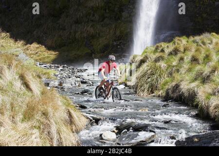 Radfahrer mit Wasserfall im Fluss Stockfoto