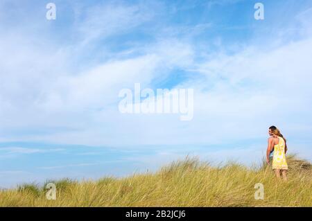 Paar, das auf grasbewachsenen Dünen steht und auf das Meer blickt Stockfoto