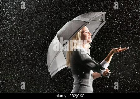 Geschäftsfrau hält sich bei Regenblick von unter dem Regenschirm ab Stockfoto