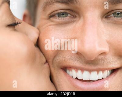 Junge Frau Küsst Wange Des Mannes Stockfoto