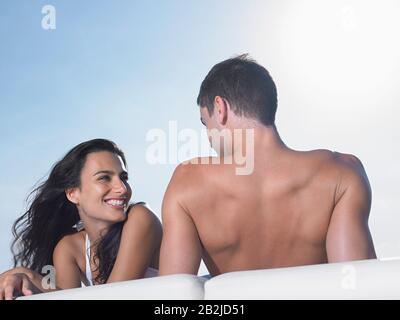 Junge Paare entspannen sich auf Kissen im Freien Stockfoto