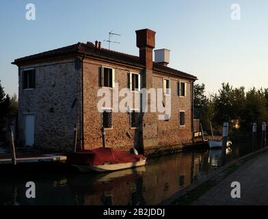 Torcello in der Abenddämmerung, ein Kanal auf der Fondamenta dei Borgognoni ein überdachtes Boot und ein Landhaus mit einem klassischen Venetian - Glockentürmchen, Venedig, Italien Stockfoto