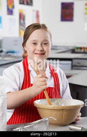 Portrait des Mädchens (10-12) mit Dem Down-Syndrom, das Inhalte in der Schüssel mischt Stockfoto