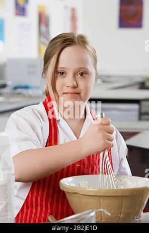 Portrait des Mädchens (10-12) mit Dem Down-Syndrom, das Inhalte in der Schüssel mischt Stockfoto