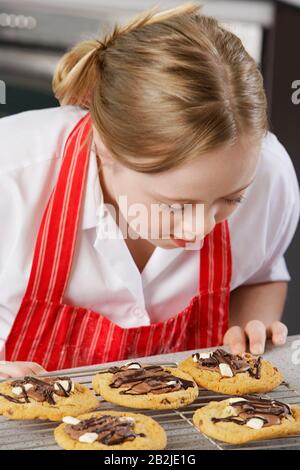 Mädchen (10-12) mit Down-Syndrom, die auf Backblech Plätzchen sehen Stockfoto