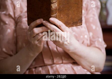 Ältere Frau sitzt im Lesebuch Stockfoto