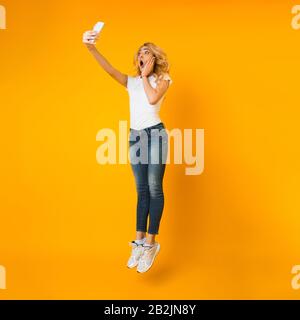 Emotionales Mädchen springt und macht selfie auf Handy Stockfoto