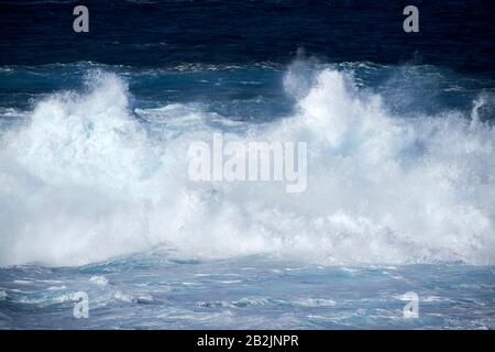 Weißer Spray und Wellen, die im Meer vor der Küste der kanarischen Inseln von Lanzarote abstürzen Stockfoto