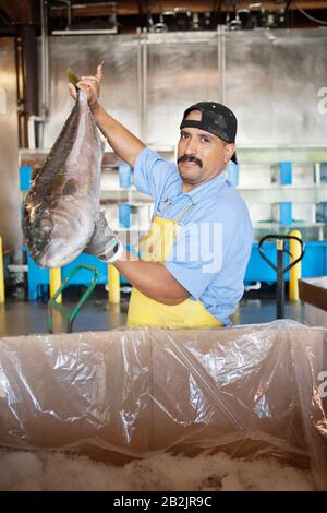 Porträt eines reifen Fischhändlers, der Lachsfische hält Stockfoto