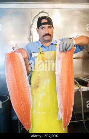 Portrait von reifen Fischhändlern, die in Scheiben geschnittenen Lachs halten Stockfoto