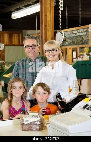 Porträt eines glücklichen Großeltern mit Kindern, die an der Kasse auf dem Markt stehen Stockfoto