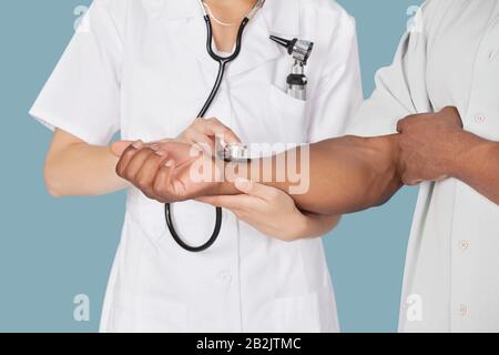 Mittelteil des Pflegepersonals, der den Puls eines Patienten über das Stethoskop überprüft Stockfoto