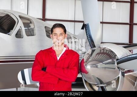 Porträt des jungen Luftfahrtingenieurs, der vor dem Flugzeug steht Stockfoto
