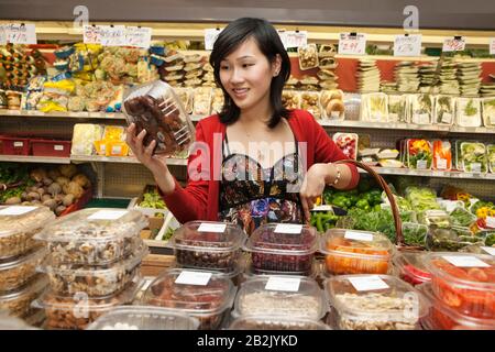 Schöne junge Frau, die auf dem Markt Produkte im Paket betrachtet Stockfoto