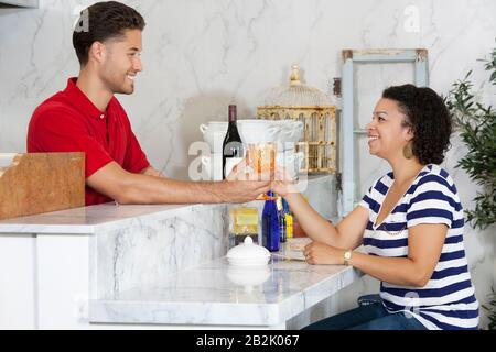 Frau übergibt leeres Glas an männlichen Kellner an der Theke Stockfoto