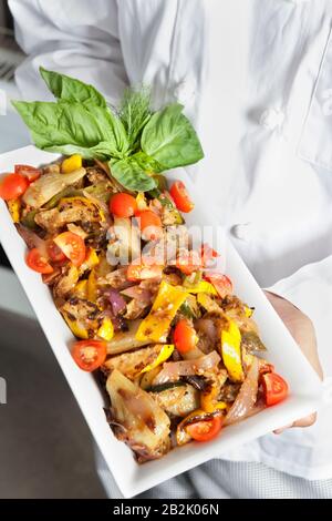 Nahaufnahme der Hände, die Salat im Serviergericht halten Stockfoto