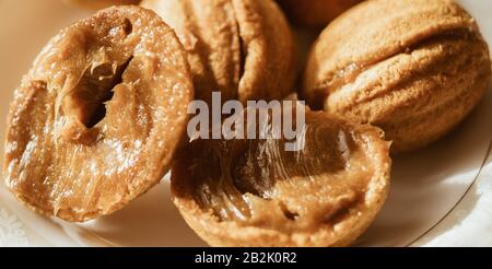 Kleine Plätzchen in Form von Walnüssen auf einer weißen Untertasse. Stockfoto