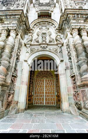 Ein Blick aus der Nähe auf einen kunstvoll geschnitzten Steineingang zu einem historischen Gebäude, mit einem großen bogenförmigen Eingang mit komplizierten Mauerwerken, einschließlich verdrehten Säulen und plastischen Reliefs. Die Tür Stockfoto