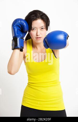 Porträt der jungen Asiatin, die Boxhandschuhe vor weißem Hintergrund trägt Stockfoto