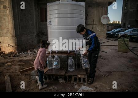 Tripolis, Libyen. März 2020. Vertriebene Kinder füllen Wasserbehälter aus einem Brunnen in einem im Bau befindlichen Gebäudekomplex, in dem Hunderte von vertriebenen Familien leben, in Tripolis, Libyen, 2. März 2020. Nach den Daten des UN-Hochkommissars für Flüchtlinge (UNHCR) sind derzeit mehr als 350.000 Libyer Binnenvertriebene. Kredit: Amru Salahuddien/Xinhua/Alamy Live News Stockfoto