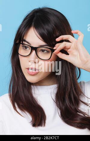 Nahaufnahme der gemischten Rasse junge Frau, die Brille über blauem Hintergrund trägt Stockfoto
