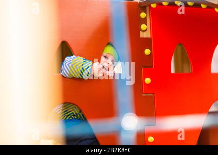 Fröhlicher kleiner Junge, der auf dem Spielplatz im Freien spielt Stockfoto