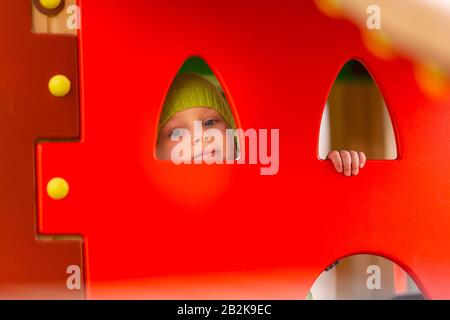 Fröhlicher kleiner Junge, der auf dem Spielplatz im Freien spielt Stockfoto