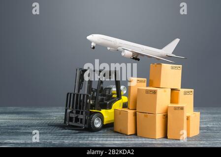 Gelber Gabelstapler und Kartonagen und Frachtflugzeug. Produktion, Transport, Frachtraum. Frachtversand. Einzelhandel. Transportlogistik Stockfoto