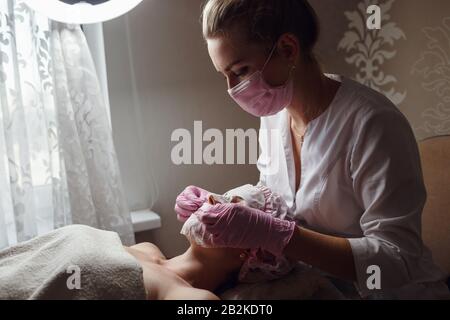 Gesunde, schöne Haut. Kosmetikerin macht Masken junges schönes Mädchen, Spa-Salon Stockfoto