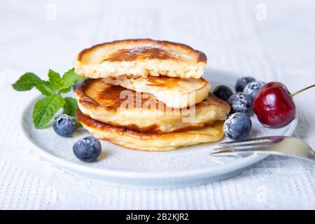 Käsekäse in der Hütte (syrniki). Hausgemachte Käsekuchen aus Hüttenkäse mit Beeren. Traditionelles russisches Gericht. Nahaufnahme. Stockfoto