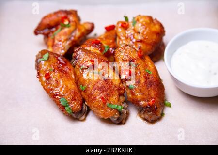 BBQ Hühnerflügel mit Sauce auf Papier. Nahaufnahme, selektiver Fokus. Stockfoto