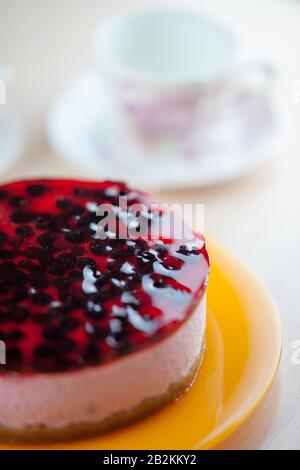 Käsekuchen in einem orangefarbenen Gericht. Auf einem verschwommenen Hintergrund Tasse für Tee. Stockfoto