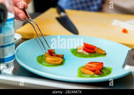 Der Koch im Restaurant bereitet ein Gericht zu, er beendet das Gericht auf einem Teller Stockfoto