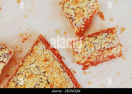 Süßer Sandtart mit Aprikosenmarmelade. In Stücke schneiden, auf einem Brett liegend mit einem Wasserkocher im Hintergrund. Teekanne mit Teetassen und süßem Kuchen Stockfoto