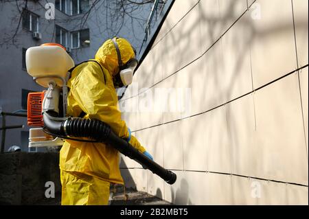 Rettungssanitäter tragen gelbes Schutzkostüm und maskieren das Desinfektionscoronavirus mit dem motorisierten Rucksackzerstäuber. Februar 26.2020. Kiew, Ukraine Stockfoto