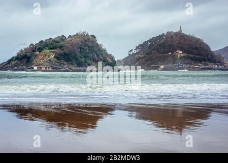 Santa Clara Island und Urgull Mount mit Jesus Christus Statue an der Bucht von La Concha am Kantabrischen Meer in der Stadt San Sebastian im baskischen Gebiet, Spanien Stockfoto