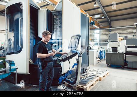 Arbeiter in der Metallindustrie, die eine moderne cnc-Drehmaschine betreibt Stockfoto