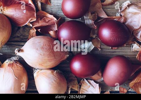 Gefärbte Ostereier mit Naturfarbstoff Zwiebel auf rustikalem Holzhintergrund gemalt. Färbevorgang mit natürlichen Farben für Ostern. Natürlich ökologisch Stockfoto