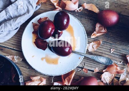 Gefärbte Ostereier mit Naturfarbstoff Zwiebel auf rustikalem Holzhintergrund gemalt. Färbevorgang mit natürlichen Farben für Ostern. Natürlich ökologisch Stockfoto