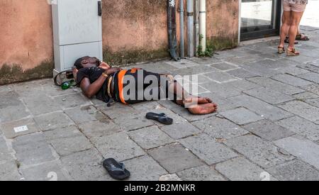 Obdachloser afrikanischer Mann, der auf der Straße schläft, Venedig, italien Stockfoto