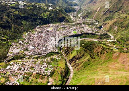 Ein Luftbild zeigt eine dicht bebaute Stadt, eingebettet in ein schmales Bergtal. Die Siedlung erstreckt sich auf beiden Seiten eines sich windenden Flusses, wobei die Gebäude eng aneinander gruppiert sind Stockfoto