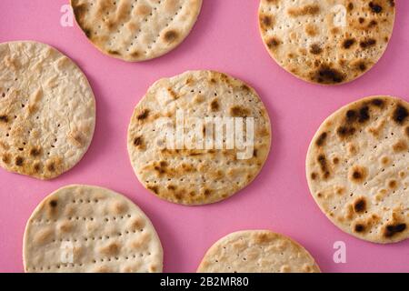Handgemachtes Matzah für das jüdische Passah auf pinkfarbenem Hintergrund Stockfoto