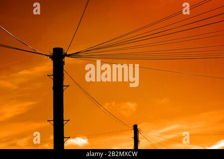Drahtlose Übertragungskabel und Pole bei Sonnenuntergang Stockfoto